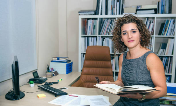 Businesswoman holding notebook sitting over desktop table