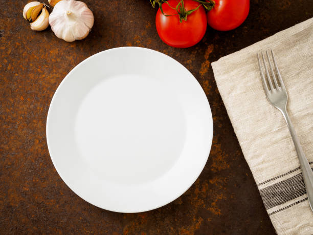 istock clean empty white plate and fork on linen napkin on rusted old iron table 909482064