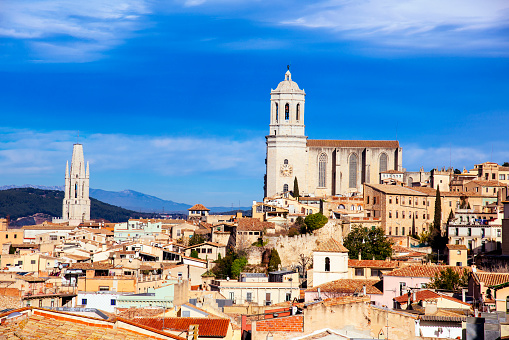 an aerial view of the Old Town of Girona, in Spain, seen from above highlighting the bell tower of the Cathedral on the right, and the bell tower of the Sant Feliu church on the left