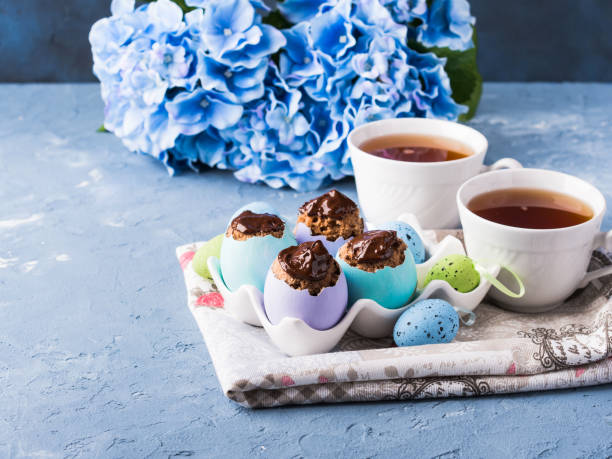 istock Easter sweet cup cakes treets in colorful egg shells on blue 909485568