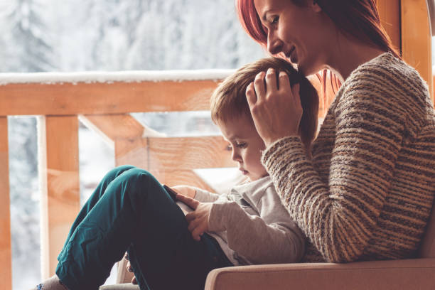 istock Mother and her son sitting in a comfortable chair with tablet 909493238