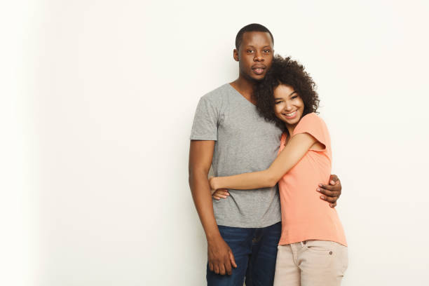 istock Smiling black couple in casual embracing at white studio background 909493520