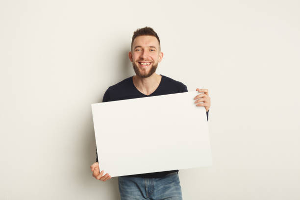 istock Young bearded man with blank white paper 909495350