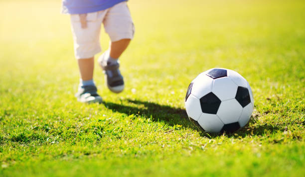 маленький мальчик играет в футбол на поле с воротами - playing field goalie soccer player little boys стоковые фото и изображения