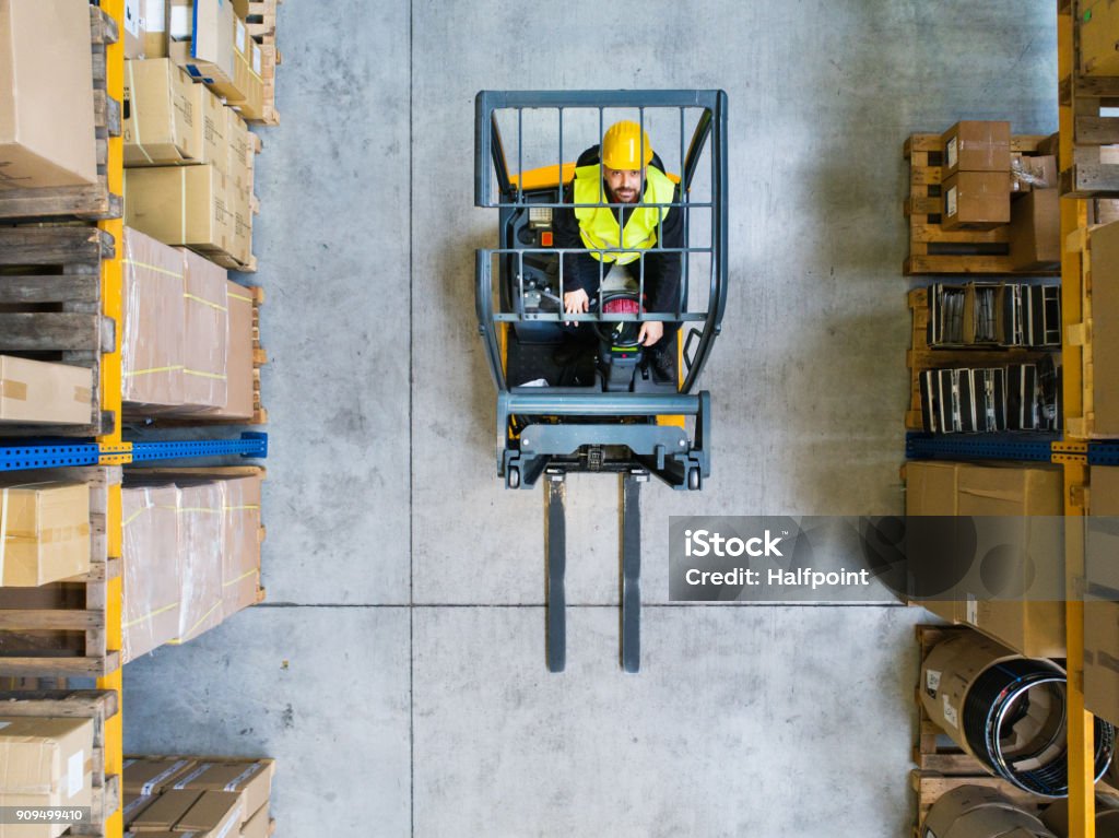 Warehouse man worker with forklift. Man forklift driver working in a warehouse. Top view. High Angle View Stock Photo