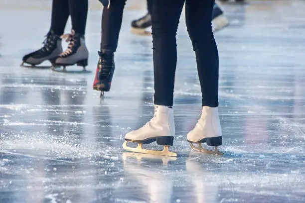 legs of boys and girls skating on winter day closeup