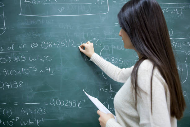 istock Female Student writing mathematical formula in front of the blackboard 909508652
