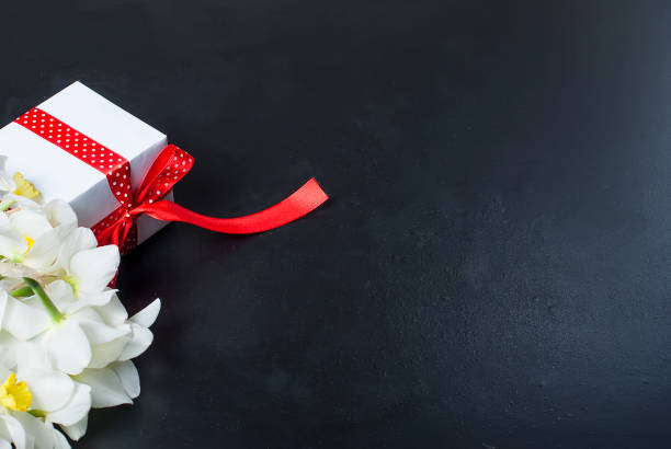 istock Bouquet daffodils and gift on the black background 909509444