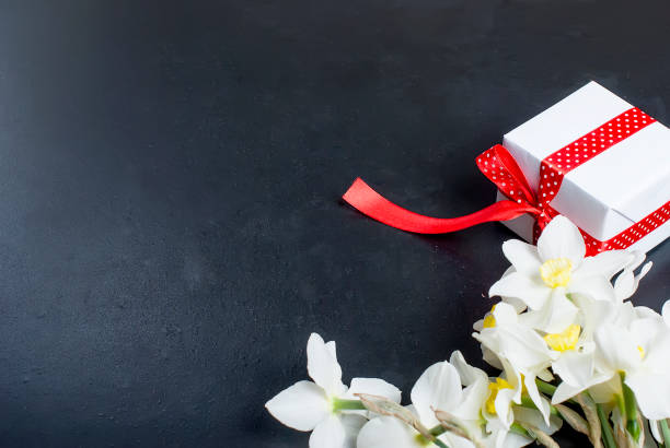 istock Bouquet daffodils and gift on the black background 909509566
