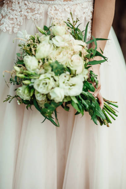 istock Bride with stunning pastel bouquet in her hands poses outside 909510284