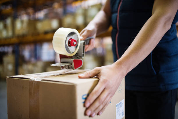 istock Male warehouse worker sealing cardboard boxes. 909512948