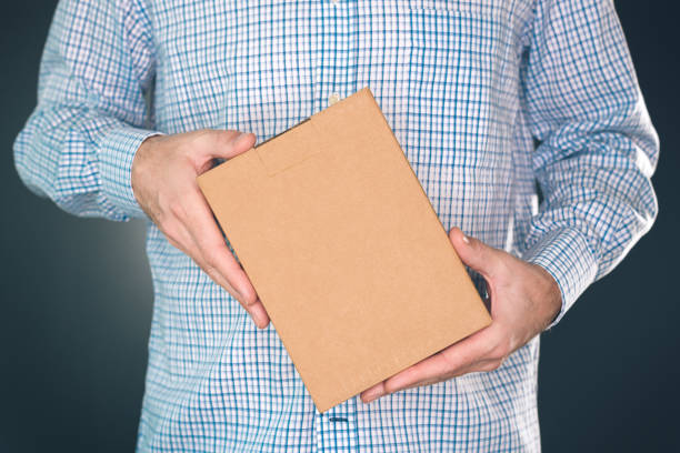 istock Man holding cardboard box package for mock up design 909513230