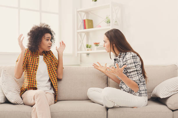 istock Two female friends sitting on sofa and arguing 909516510