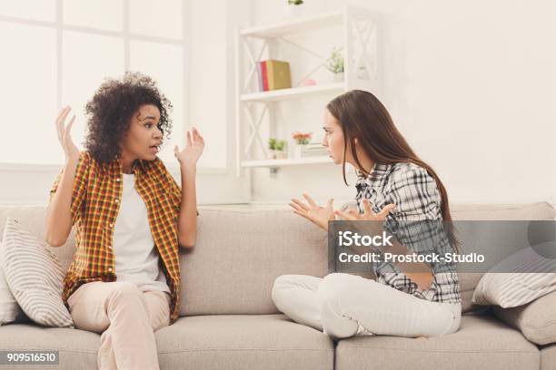 Two Female Friends Sitting On Sofa And Arguing Stock Photo - Download Image Now - Arguing, Only Women, Women