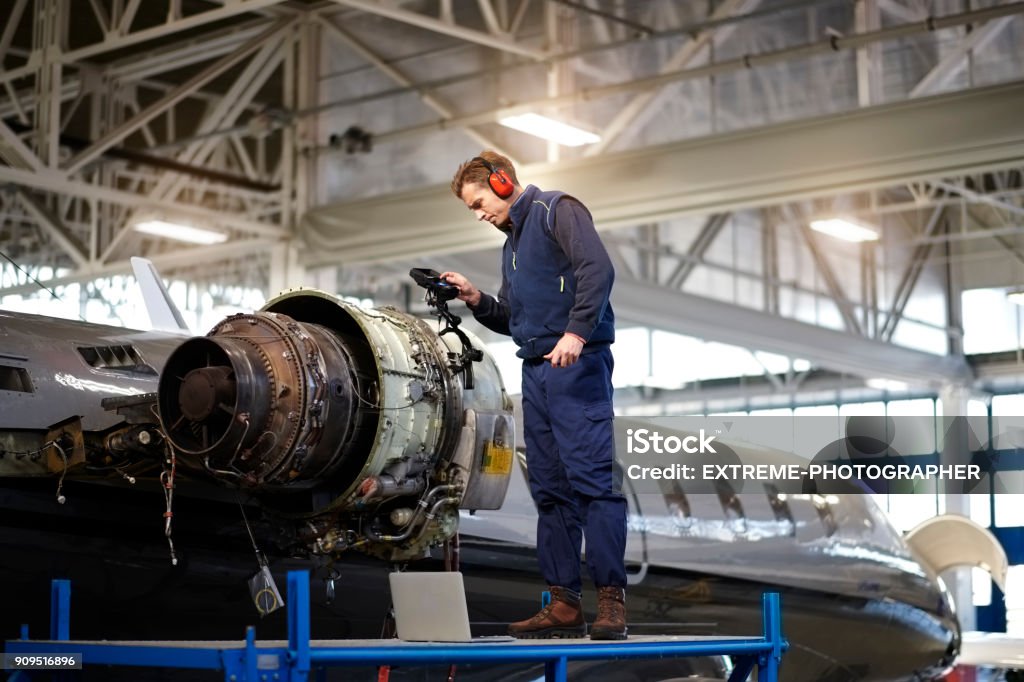Aircraft mechanic in the hangar Aircraft engineer in the hangar repairing and maintaining airplane jet engine. Aerospace Industry Stock Photo