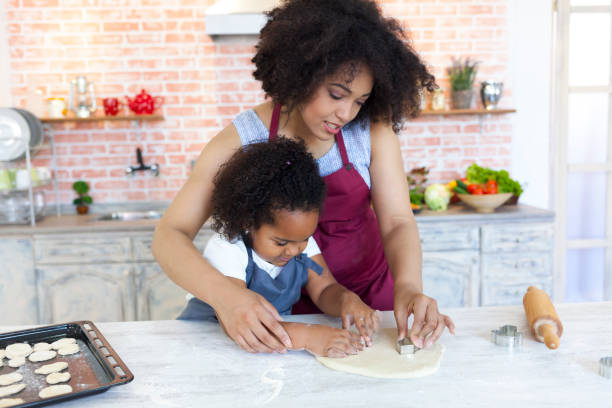istock Mother and daughter preparing dough for homemade biscuits 909517554