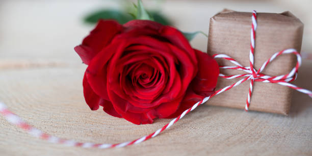 istock Red rose with gift on bright rustic wood 909518620