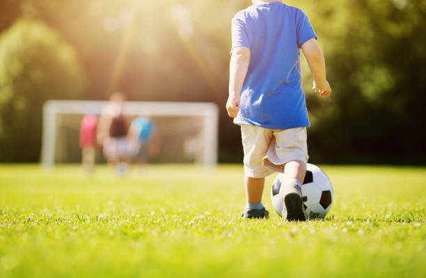 маленький мальчик играет в футбол на поле с воротами - soccer child little boys playing стоковые фото и изображения