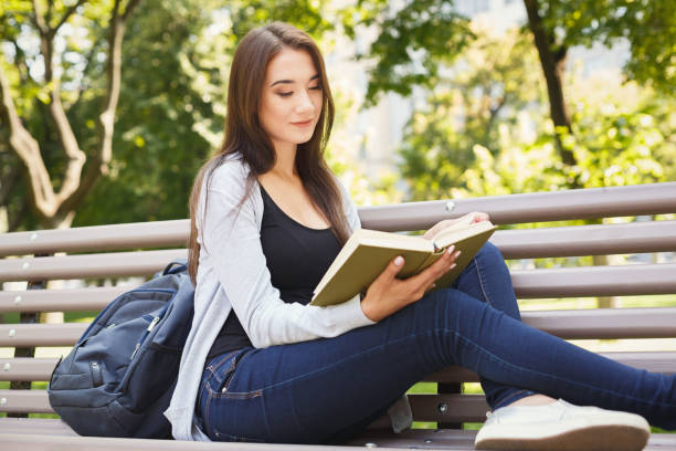 istock Young woman reading book in park copy space 909519226