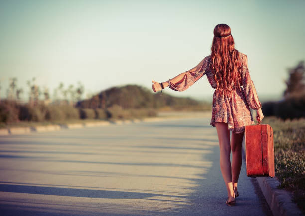 Young hippie woman hitchhiking on a road. Rear view Young hippie woman hitchhiking on the road. Rear view hitchhiking stock pictures, royalty-free photos & images