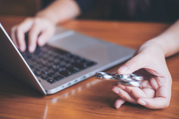 A woman using labtop while playing fidget spinner on vintage wooden table