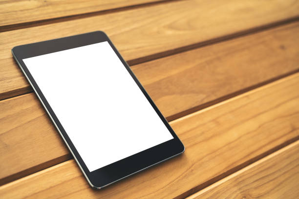 istock Mockup image of black tablet pc with blank white screen on vintage wooden table background 909529992