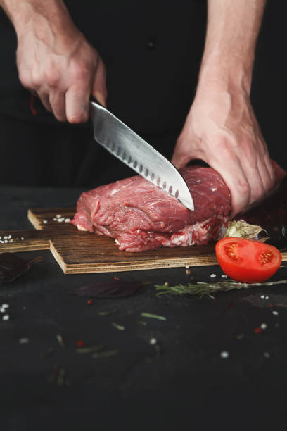 istock Chef cutting filet mignon on wooden board at restaurant kitchen 909538262