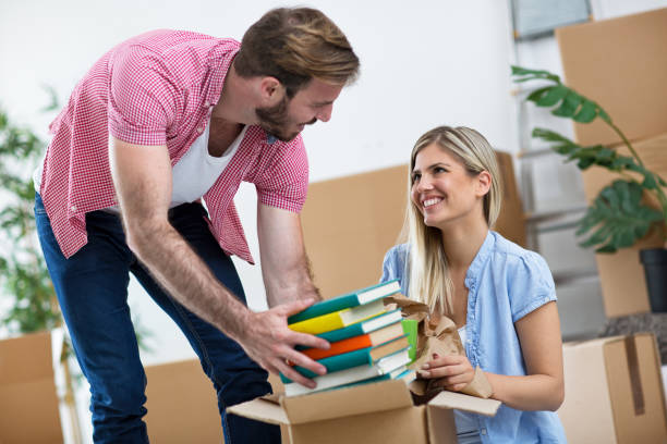 istock Young couple packs books in the boxes 909545530