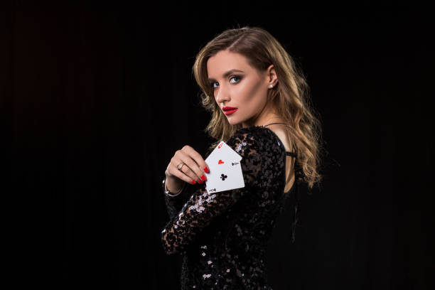 Young woman holding playing cards against a black background stock photo