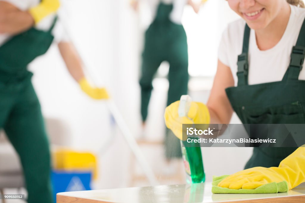 Close-up of smiling charwoman Close-up of smiling charwoman holding cleaning liquid in yellow gloves Cleaning Stock Photo