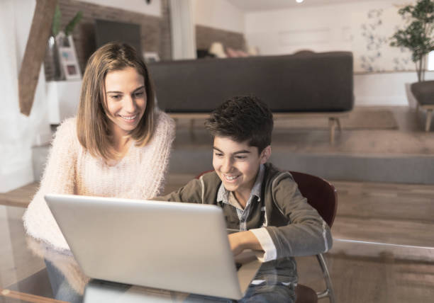 istock Mother helping her son with laptop computer at home 909551132