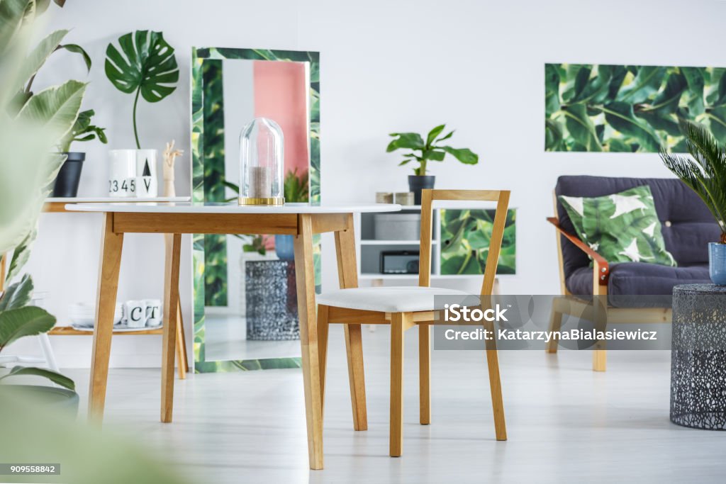 Floral dining room interior Wooden chair at dining table in floral room interior with leaf, mirror and green poster on white wall Dining Stock Photo