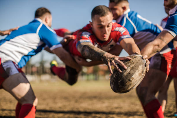 Group of men playing rugby outdoors,one of them jumping with the ball in his hands