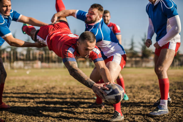 Jumping to win Group of men playing rugby outdoors,one of them jumping with the ball in his hands rugby team stock pictures, royalty-free photos & images