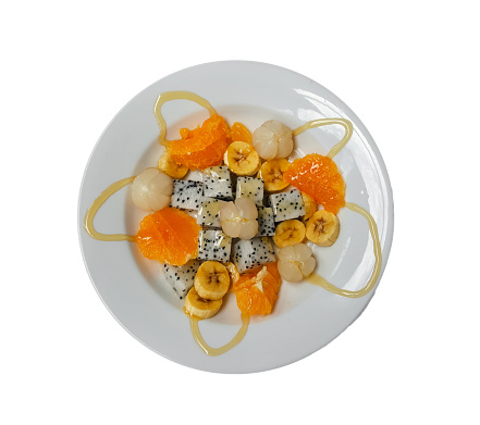 Mixed fruits with honey bee in the plate over white background, orange with dragon fruit, Wollongong and banana, Top view of healthy food concept, include clipping path