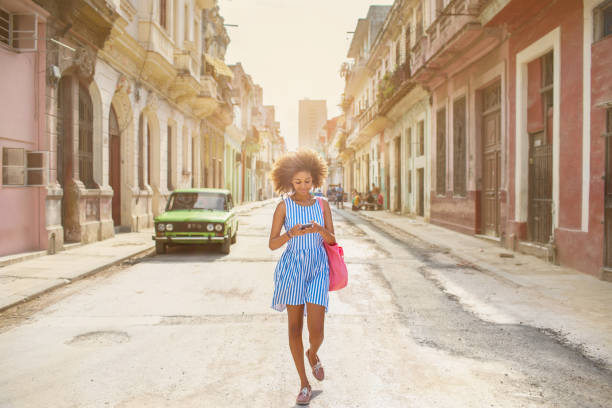 Cuban girl looking at mobile phone, walking down street in Havana Young woman, Cuban life, Havana cuban culture photos stock pictures, royalty-free photos & images
