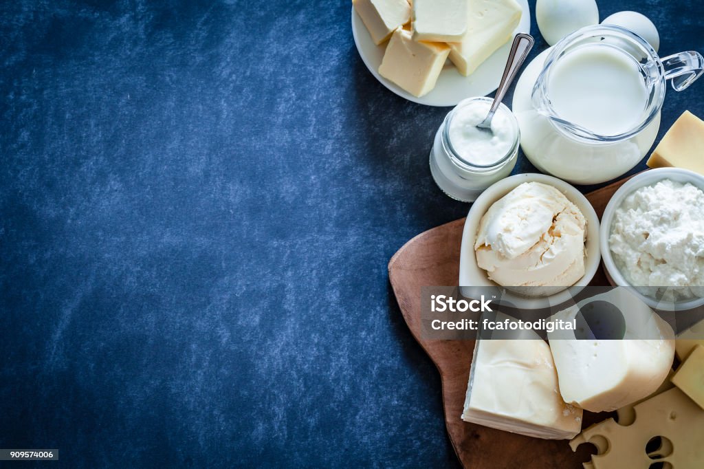 Dairy products shot on bluish tint background Top view of dairy products assortment shot on bluish tint kitchen table. The composition is at the right of an horizontal frame leaving useful copy space for text and/or logo. Dairy products included are milk, yogurt, butter, mozzarella, mascarpone, emmental cheese, ricotta, eggs and goat cheese. DSRL studio photo taken with Canon EOS 5D Mk II and Canon EF 100mm f/2.8L Macro IS USM Dairy Product Stock Photo