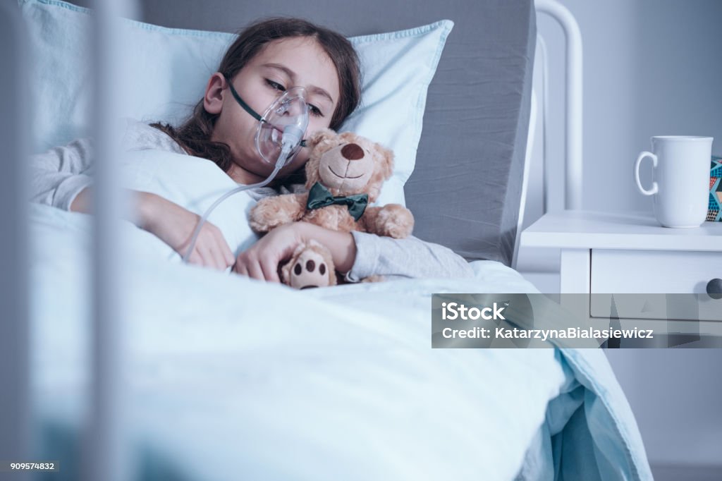 Kid with oxygen mask Kid with cystic fibrosis lying in hospital bed with oxygen mask and plush toy Child Stock Photo