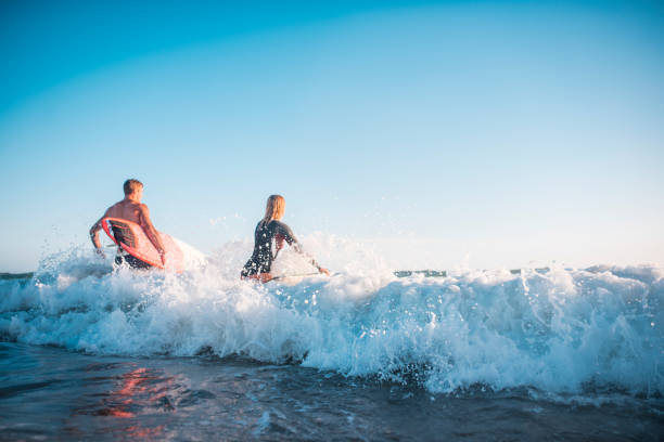 istock Young friends going into the water with their surfboards 909575052