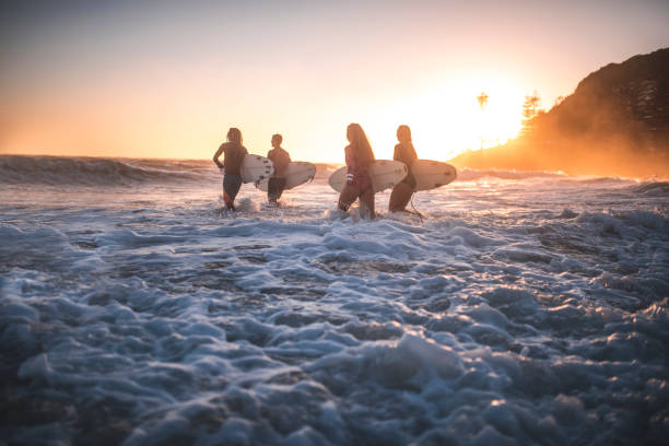 istock Friends running into the ocean with their surfboards 909575074