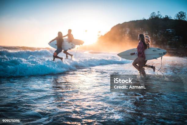 Friends Running Into The Ocean With Their Surfboards Stock Photo - Download Image Now