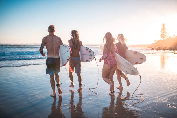 istock Friends running into the ocean with their surfboards 909575104