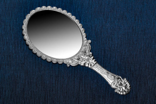 istock Antique retro hand mirror isolated on dark blue background 909577868