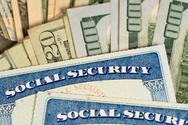 USA Social security cards laid on dollar bills USA Social security cards laid on pile of dollar bills to illustrate money in retirement unemployment stock pictures, royalty-free photos & images