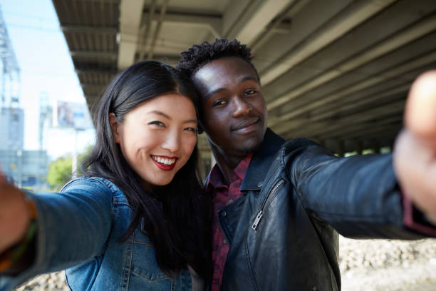 istock Multi ethnic couple making selfie near railway 909606308