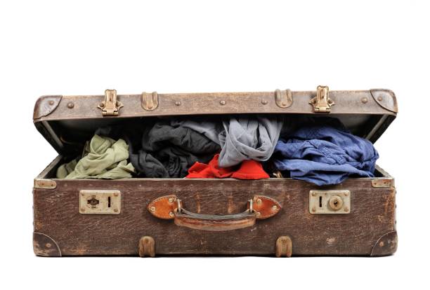 istock Old suitcase full of clothes isolated on white background 909606560