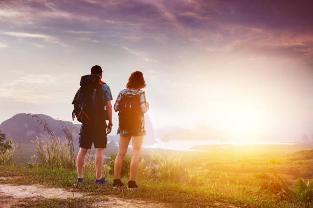 mochileiros de casal assistir ao nascer ou o pôr do sol, perto do mar baía e ilhas - sunrise beach couple hiking - fotografias e filmes do acervo