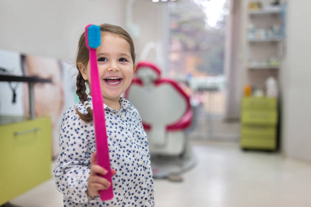 Playing with a big toothbrush Lovely toddler visiting the dentist, having an examination. pediatric dentistry stock pictures, royalty-free photos & images