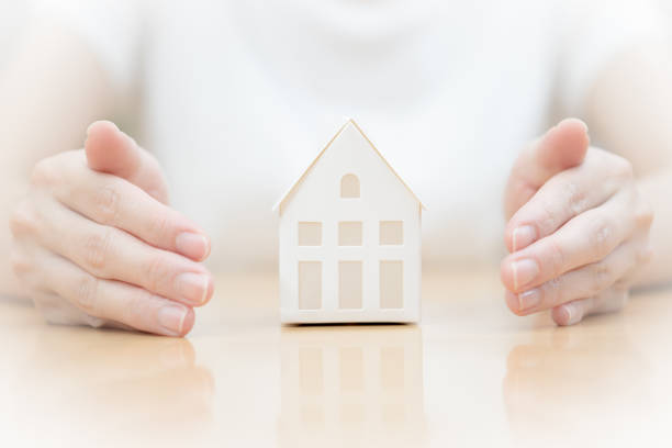 istock Female hands saving Miniature House 909634470