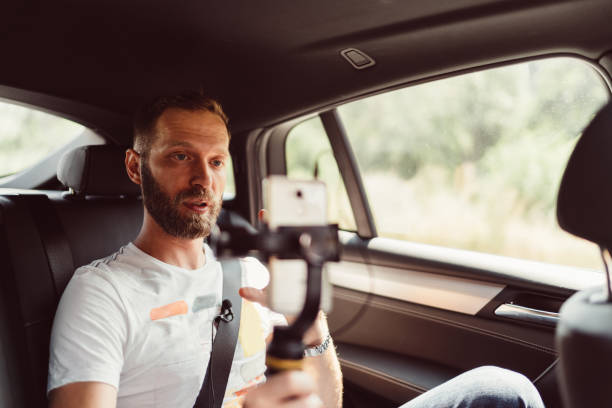 Man vlogging in taxi Young man recording a video for the social media while traveling in car reportage stock pictures, royalty-free photos & images